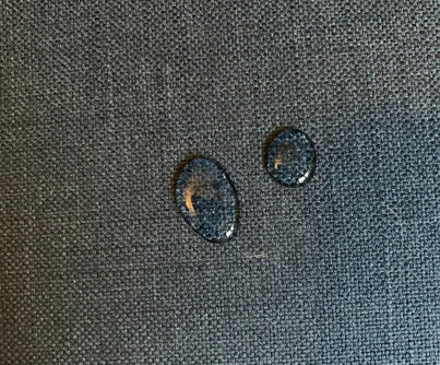 Water droplets on a textured dark fabric background.