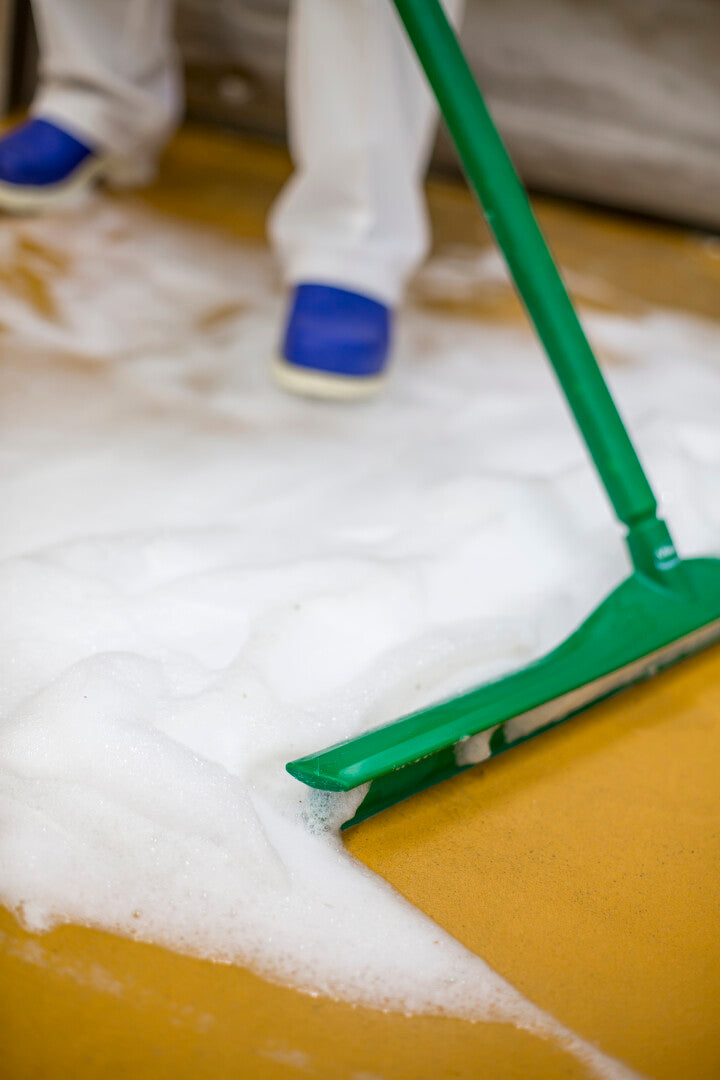 Green Vikan Ultra Hygiene Squeegee cleaning a soapy floor.