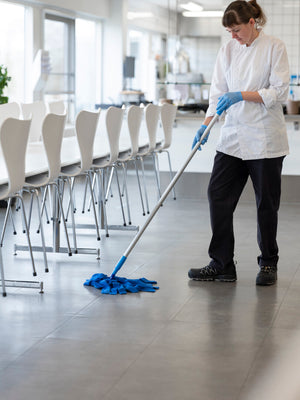 A person mopping a floor with a blue Vikan Microfibre Socket Mop in a kitchen.