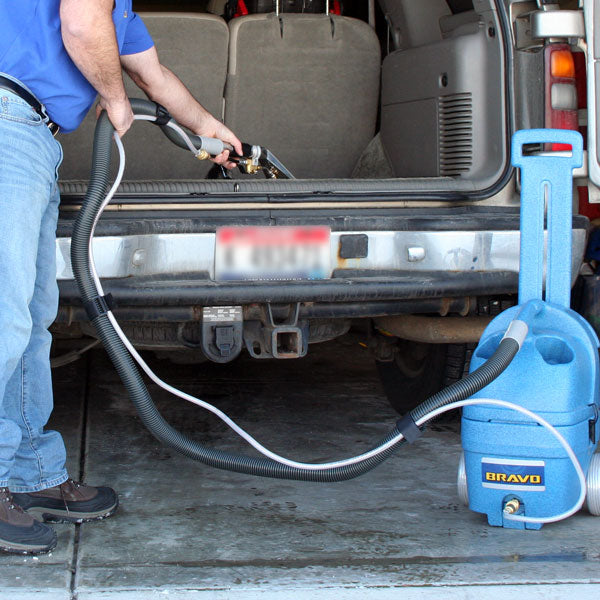 Person using a Prochem Bravo Plus BV300 carpet extractor in a vehicle's trunk.