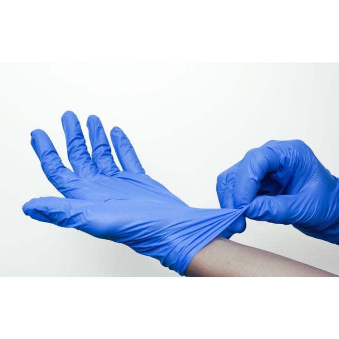 Person putting on a blue vinyl disposable glove from a pack.