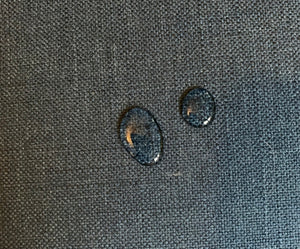 Water droplets on a textured dark fabric background.