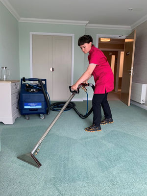 Person using a Steemeasy PR200 Carpet Cleaner on green carpet in a room.