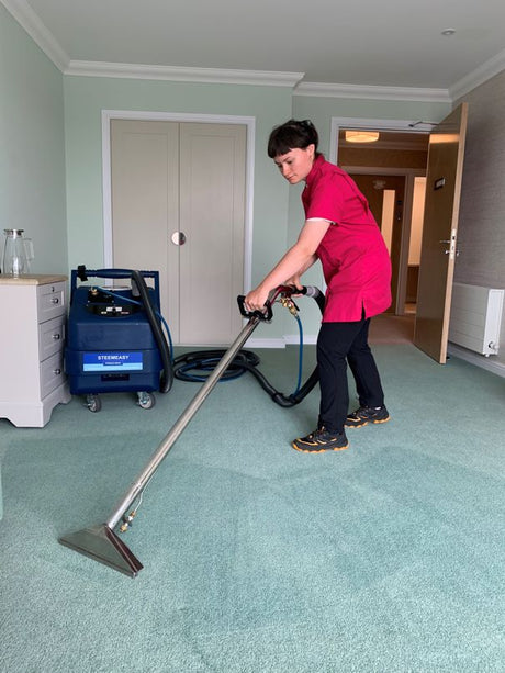 Person using a Steemeasy PR200 Carpet Cleaner on green carpet in a room.